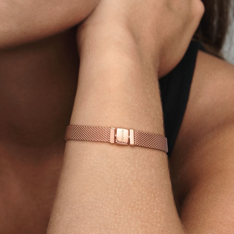 Pandora Reflexions™ Mesh Bracelet - Pandora West Africa Bracelets Pandora Reflexions is a modern way to reflect who you are. The Reflexions Mesh Bracelet holds clip-on charms that sit flush to mirror your style – whatever shape it takes. Plated with 14k rose gold for a blush-pink finish, this piece looks equally cool worn alone or stacked with other bracelets. Weave your story into your style and go gold and bold, adding your favourite charms from the collection. (587712-20)  